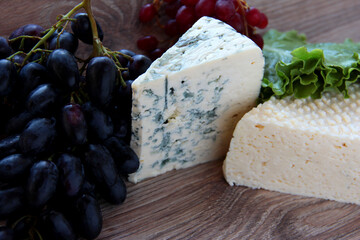 A piece of blue cheese and grapes. Gourmet products.