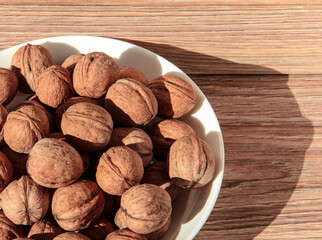 Walnuts in a white bowl on a wooden background.