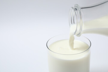 Pouring milk into glass on white background, closeup