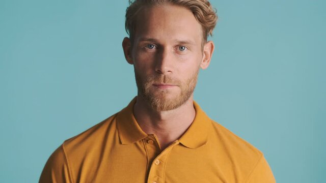Young handsome blond bearded man intently looking in camera over colorful background