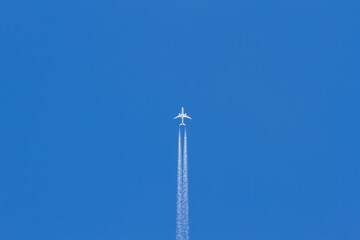 Jet plane flying in the blue sky. Wake leaving trace or steam jet, viewed from below in nadir shot