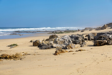 Empty sunny beach with bathers and rocks in the sand