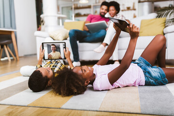 Family at home.African american boy and girl lying on floor and using digital tablet.
