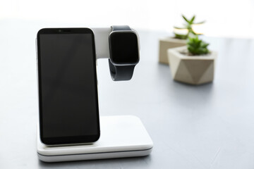 Stylish smart watch and phone charging with wireless pad on grey table