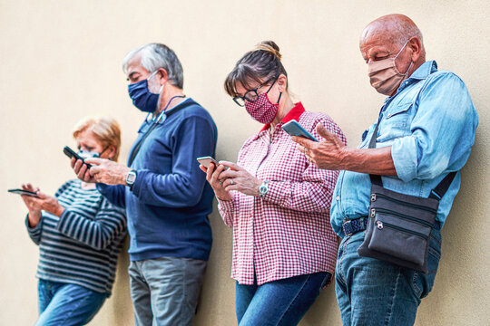 Senior people using smartphones with face mask on - Old man in focus
