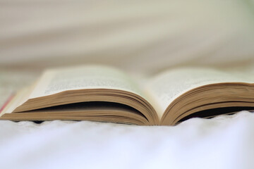 Open book on a bed. Selective focus.