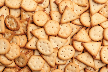 Many delicious crackers as background, top view