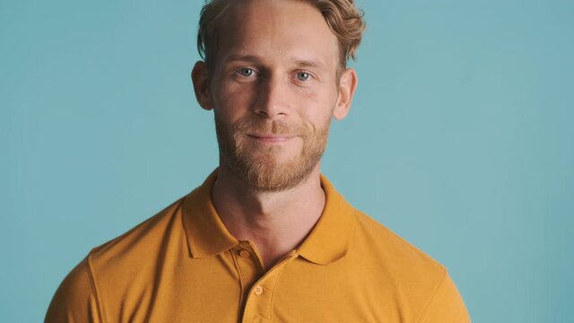 Attractive blond bearded man confidently posing on camera over colorful background