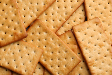 Many delicious crackers as background, top view