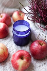 autumn still life, candle and apples on white knitted background, cosy home