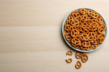 Delicious pretzel crackers on wooden table, flat lay. Space for text