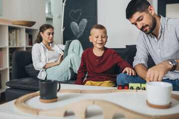 happy family playing with the wooden toy train at home