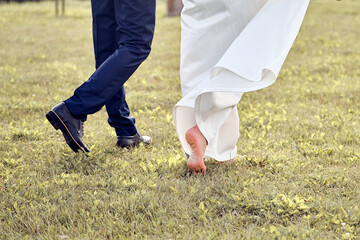 Man and woman walk barefoot on the grass