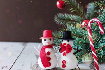 A couple of snowmen standing on wooden floor near Christmas tree.