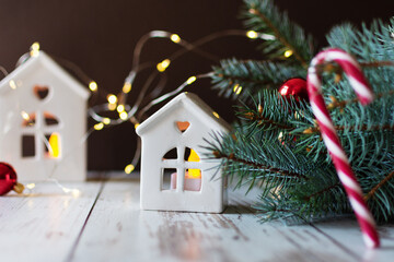 Fototapeta na wymiar Christmas candlestick in a house shape on wooden floor near fir tree over Christmas lights.