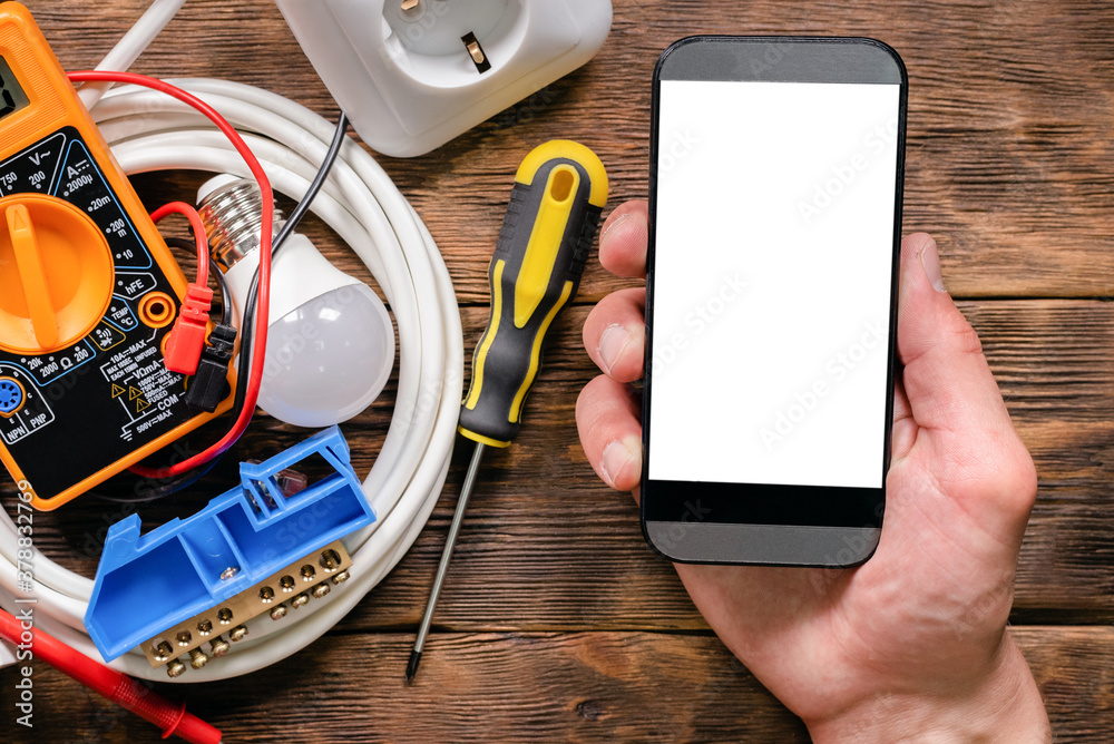 Wall mural Mobile phone with blank screen in the electrician hands close up.