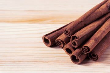 Close-up of cinnamon sticks on light wooden background. Selective focus, shallow depth of field.