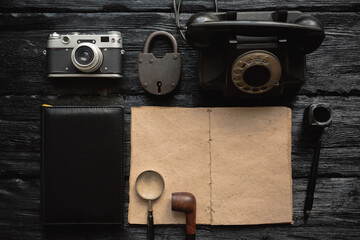 Detective story book template. Blank paper page with copy space and other retro accessories on the black table background.