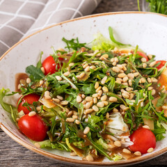 Dieta and healthy arugula  salad with  pine nuts, tomatoes and cheese. Closeup