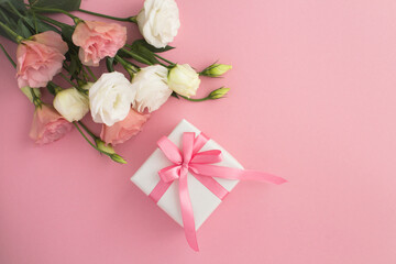 White gift box, beautiful white and pink flowers on the pink  background  top view  copy space