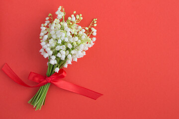 Bouquet of lilies of the valley  with red bow on the red background  top view copy space