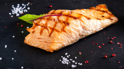Grilled salmon fillet with lemon on a balck stone. background. Macro view. Closeup