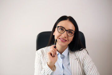 Portrait of smiling pretty young business woman in glasses sitting on workplace