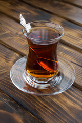 Turkish tea in the glass on the brown wooden background closeup
