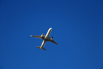 Fototapeta na wymiar Airplane flying high in the clear blue sky - low angle view