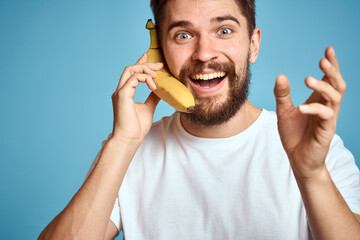 a man with a banana is caught in a white t-shirt on a blue background concept of communication by phone