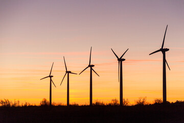 Wind Turbines at Dusk. Landscape sunset with windmills. Renewal source of electricity. Wind turbines field new technology for clean energy on mountain, sunset view with colorful twilight on sky.