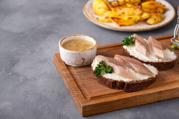 Sandwich with herring. Tasty appetizer on a wooden board. Copy space