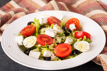 Diet salad with fresh vegetables. Tomatoes, quail eggs, lettuce,  cheese and black olives. Healthy food concept.