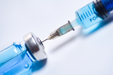 Medical syringe and blue vial vaccine on white background with selective focus and crop fragment
