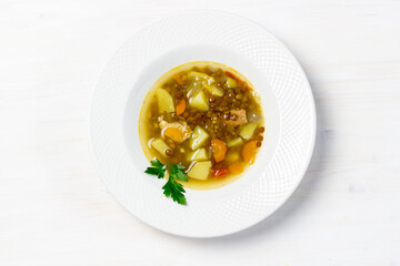 chicken, pork, lentil soup with vegetables in white bowl
