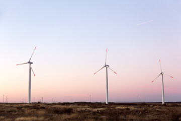 Wind Turbines at Dusk. Landscape sunset with windmills. Renewal source of electricity. Wind turbines field new technology for clean energy on mountain, sunset view with colorful twilight on sky.