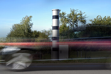 Long exposure at a speed measuring device and a fast passing car in motion blur, traffic monitoring...