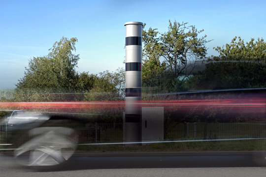 Long exposure at a speed measuring device and a fast passing car in motion blur, traffic monitoring with light radar and camera to punish speeding with fines or revocation of driving license