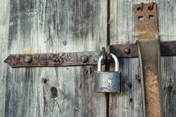 old wooden door with a padlock and rusty plates