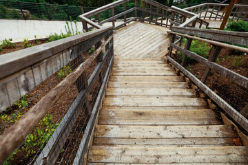 Long and steep wooden walkway stairway of several stair steps with railings