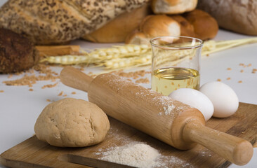 Eggs and dough with rolling pin on cutting board