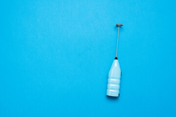 Milk frother tool on the blue flat lay background with copy space.