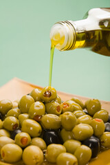 Olive oil being poured on black and green olives