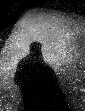 la sombra de un hombre sobre el asflato en la noche