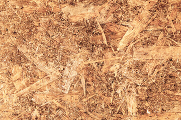 Oriented Strand Board. Chipboard building material. OSB wooden panel made of pressed sandy brown wood shavings as background closeup