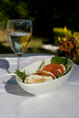 Close-up of fresh mozzarella and tomato salad with a glass of wine