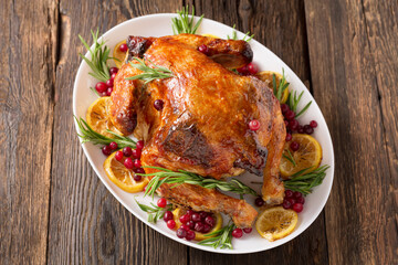 Thanksgiving Day traditional dish baked turkey. Roasted turkey or chicken with orange slices in plate for Christmas dinner on dark rustic background, top view, close up