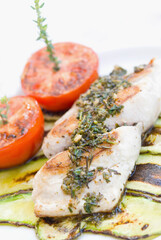 High angle view of grilled fish with zucchini and tomatoes