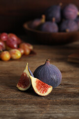 Whole and cut tasty fresh figs on wooden table