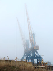 Harbor crane. Two old rusty cranes in an industrial port in the fog.